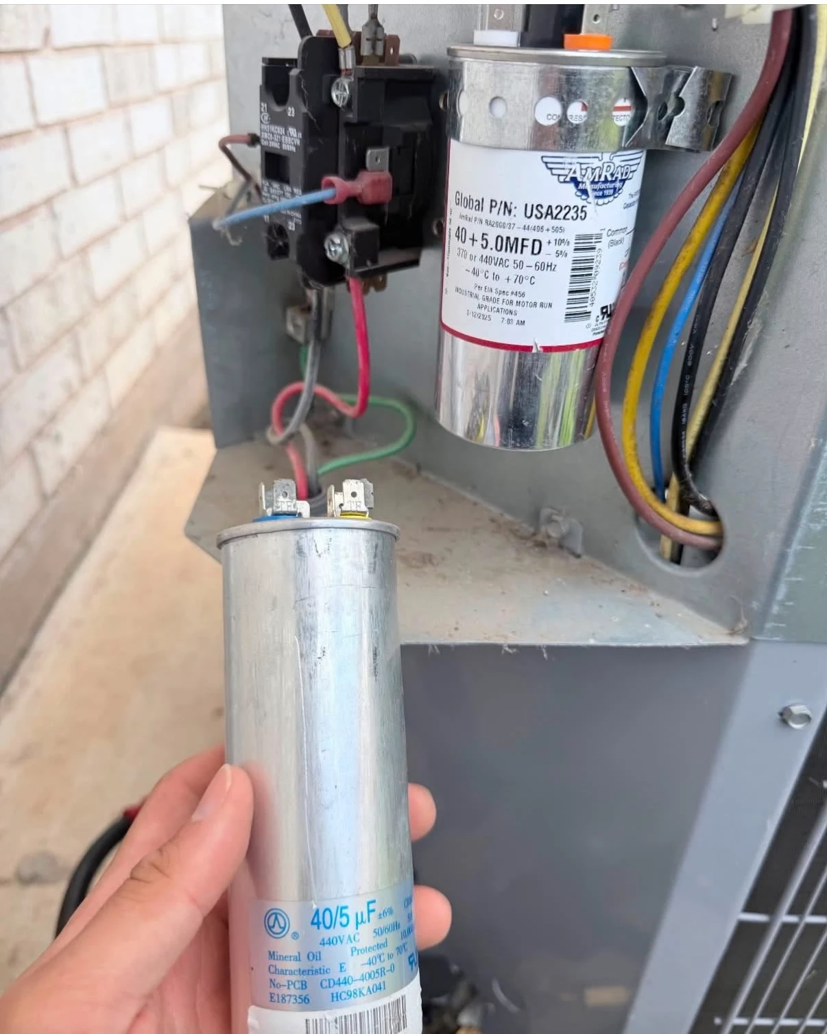 HVAC services Pflugerville TX technician holding a capacitor for air conditioning unit repair.